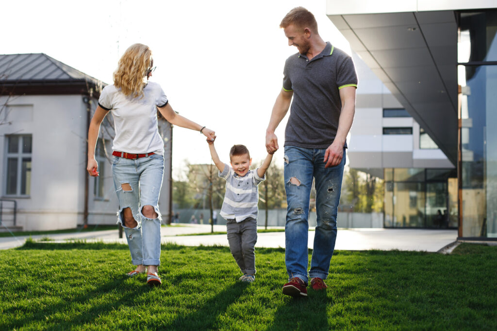 A happy family enjoying a walk on a lush green lawn outside a modern commercial building, representing a vibrant and growing business environment.